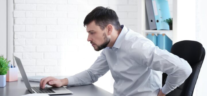 posture-concept-man-suffering-from-back-pain-while-working-with-laptop-office