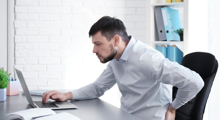 posture-concept-man-suffering-from-back-pain-while-working-with-laptop-office